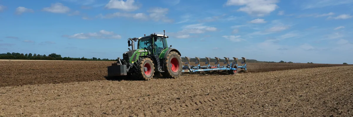 Tracteur dans un champ symbolisant les ingrédients locaux des croquettes Colonel Gustave super premium pour chiens et chats fabriquées en Belgique.